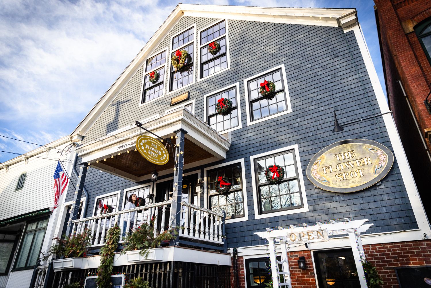 The 1850s house in Richmond, Maine — blue-gray shingles, white balcony, and a wreath in every window
